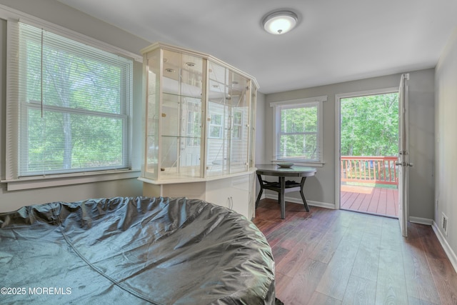 bedroom featuring access to outside, wood finished floors, and baseboards