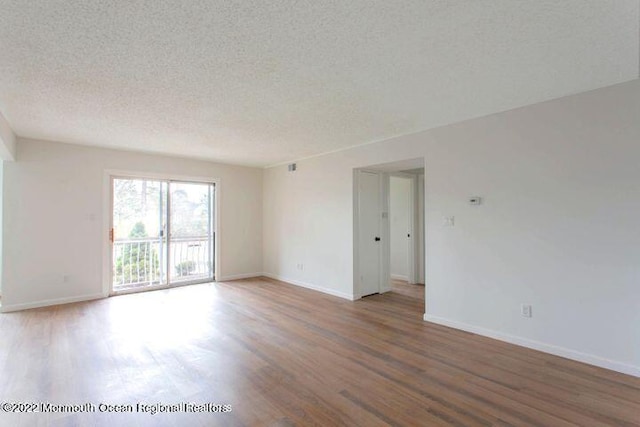 spare room featuring wood finished floors, a textured ceiling, and baseboards