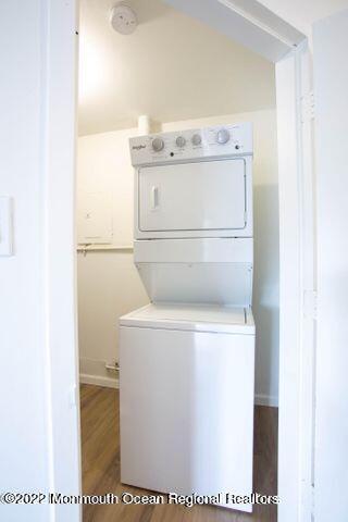 washroom featuring stacked washer / drying machine and wood finished floors