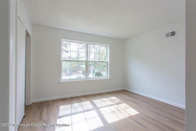 unfurnished bedroom with light wood-type flooring, a textured ceiling, baseboards, and a closet