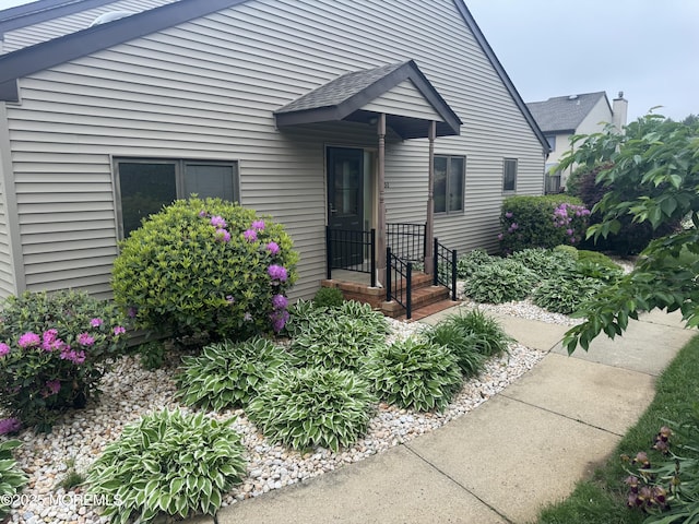 entrance to property featuring roof with shingles
