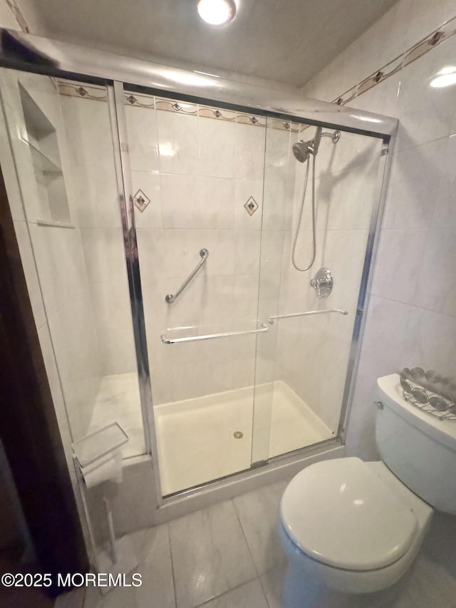 full bathroom with toilet, a stall shower, and tile walls