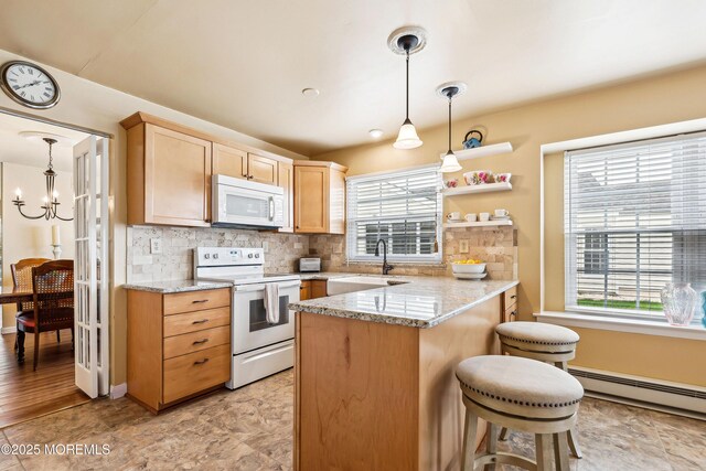 27 Gladstone Ave, Manchester, NJ 08759 - kitchen with white appliances, a peninsula, a breakfast bar area, backsplash, and baseboard heating