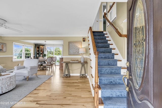 entrance foyer with wood finished floors, stairs, crown molding, baseboard heating, and baseboards