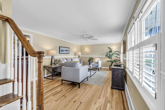 living room with light wood-style floors, stairs, crown molding, ceiling fan, and baseboards