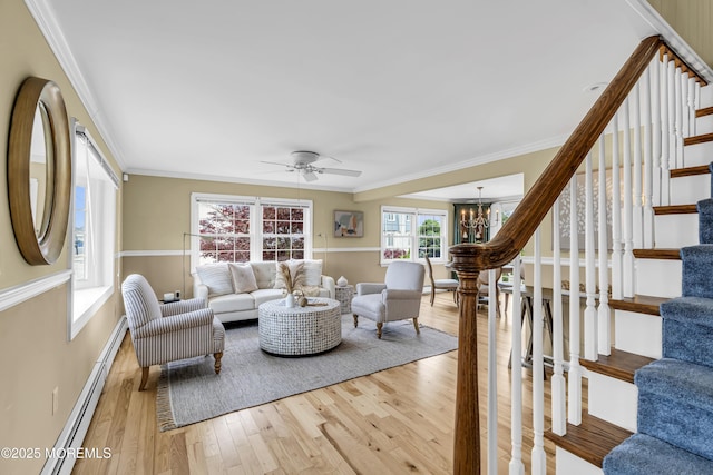 living room with a chandelier, wood finished floors, stairway, ornamental molding, and a ceiling fan