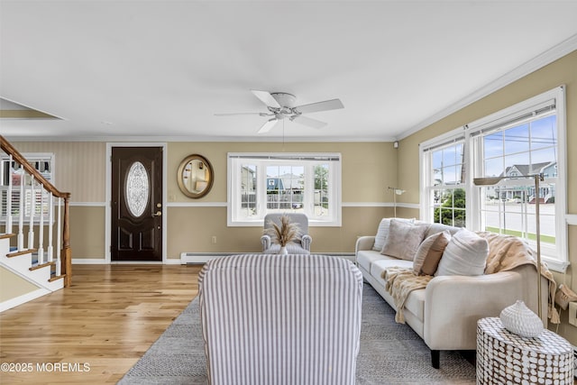 living area with light wood-style flooring, stairs, a ceiling fan, crown molding, and baseboards