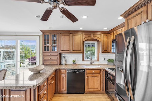 kitchen featuring black appliances, a sink, brown cabinets, a peninsula, and a ceiling fan