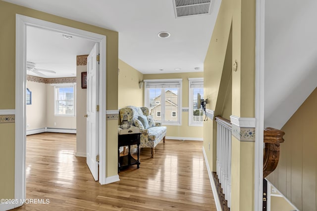 hall featuring light wood finished floors, baseboards, and a baseboard heating unit