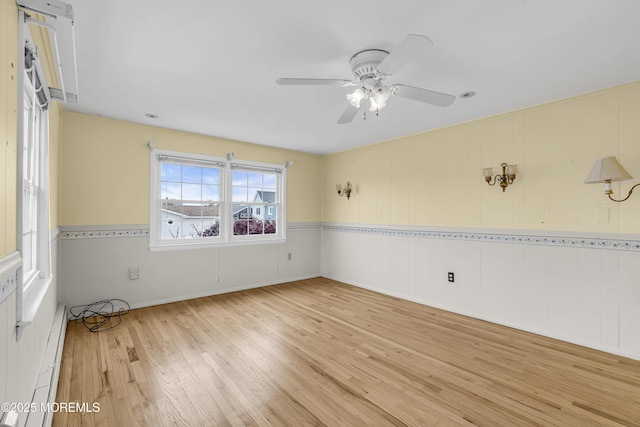 empty room with light wood-style floors, baseboard heating, and a ceiling fan