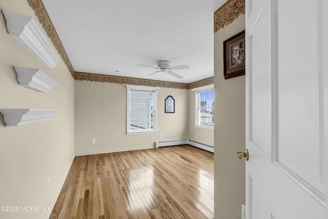 unfurnished room featuring wood-type flooring, ceiling fan, a baseboard heating unit, and baseboards