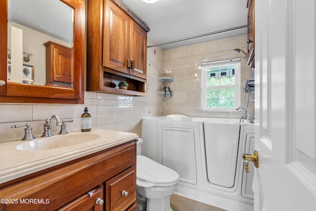 bathroom featuring washing machine and clothes dryer, tasteful backsplash, toilet, vanity, and tile patterned floors