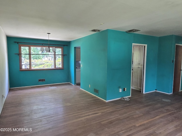 empty room featuring a chandelier, wood finished floors, and baseboards