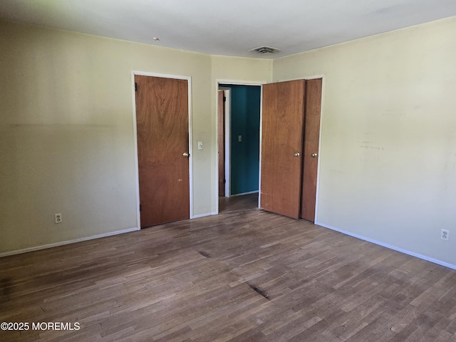 unfurnished bedroom featuring wood finished floors, baseboards, and a closet