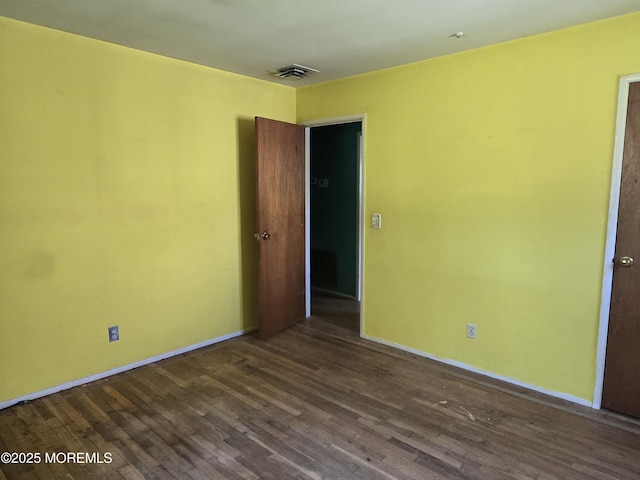 empty room featuring dark wood-style flooring and baseboards