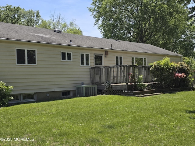 back of property with central AC, a deck, a yard, and a shingled roof