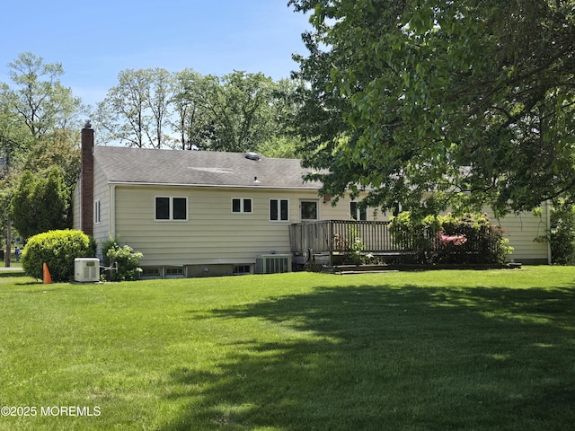 rear view of property with a yard, a wooden deck, a chimney, and cooling unit