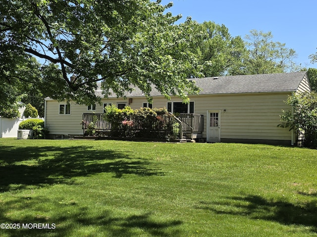 back of property featuring a deck, a yard, cooling unit, and roof with shingles