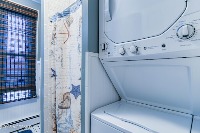 laundry area featuring a baseboard heating unit and stacked washer / drying machine