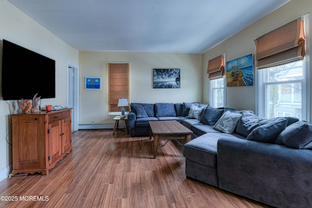 living area with wood finished floors, a baseboard heating unit, and baseboards