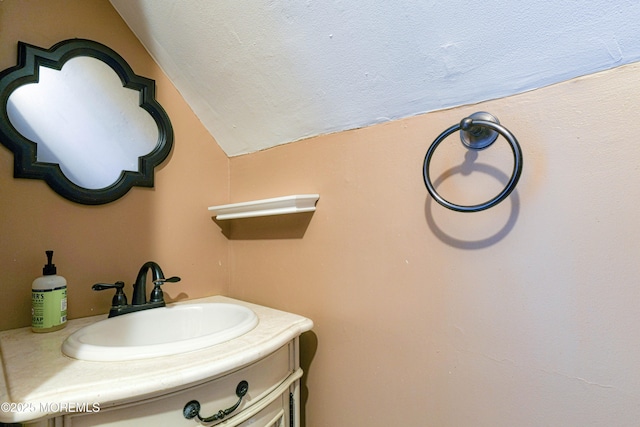bathroom with vaulted ceiling, vanity, and a textured ceiling