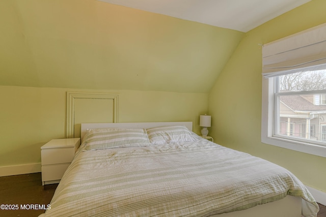 bedroom featuring lofted ceiling, baseboards, and dark wood-style floors