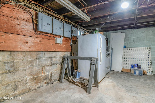 unfinished below grade area with freestanding refrigerator, electric panel, and washer / dryer