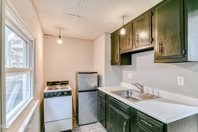 kitchen featuring freestanding refrigerator, white range with electric stovetop, green cabinets, a sink, and plenty of natural light