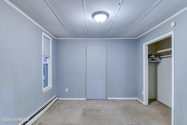 unfurnished bedroom with baseboard heating, carpet flooring, a closet, and baseboards