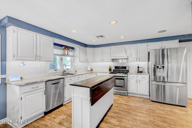 55 Yorktowne Dr, Manalapan, NJ 07726 - kitchen with stainless steel appliances, a sink, premium range hood, white cabinets, and light wood finished floors