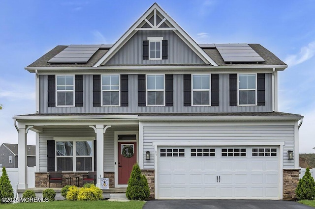 83 Weston Dr, Woolwich, NJ 08085 - view of front of property featuring covered porch, board and batten siding, solar panels, and stone siding