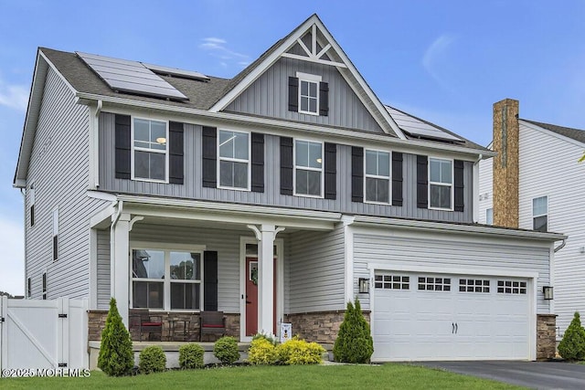 83 Weston Dr, Woolwich, NJ 08085 - view of front facade featuring covered porch, roof mounted solar panels, board and batten siding, and stone siding