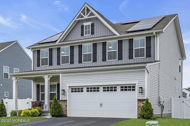 83 Weston Dr, Woolwich, NJ 08085 - view of front of house featuring board and batten siding, solar panels, a garage, and stone siding