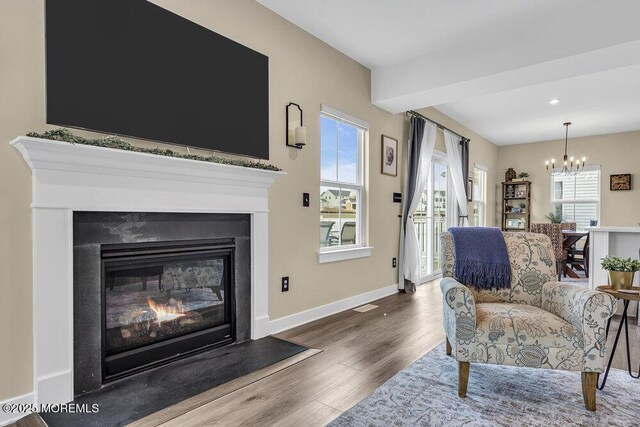 83 Weston Dr, Woolwich, NJ 08085 - living room with a chandelier, a glass covered fireplace, wood finished floors, beamed ceiling, and baseboards