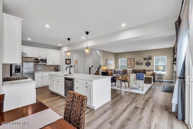 83 Weston Dr, Woolwich, NJ 08085 - kitchen featuring appliances with stainless steel finishes, light wood-style floors, a sink, tasteful backsplash, and a center island with sink