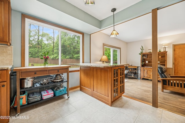 325 Oak Hill Rd, Red Bank, NJ 07701 - kitchen featuring brown cabinetry, light stone counters, light tile patterned flooring, a peninsula, and hanging light fixtures