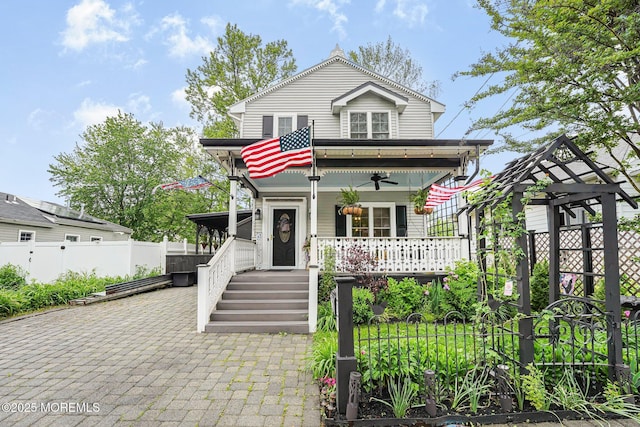 view of front facade featuring covered porch, a ceiling fan, and fence