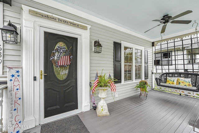 view of exterior entry featuring a porch and a ceiling fan