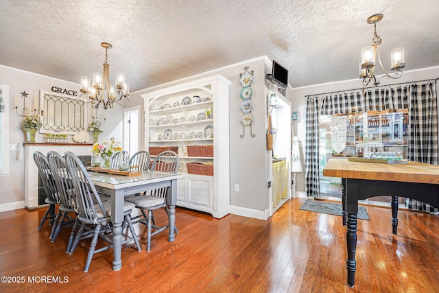 dining room with a chandelier, baseboards, wood finished floors, a textured ceiling, and healthy amount of natural light