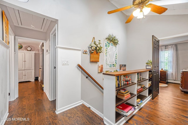 hall with attic access, a baseboard heating unit, an upstairs landing, dark wood finished floors, and baseboards