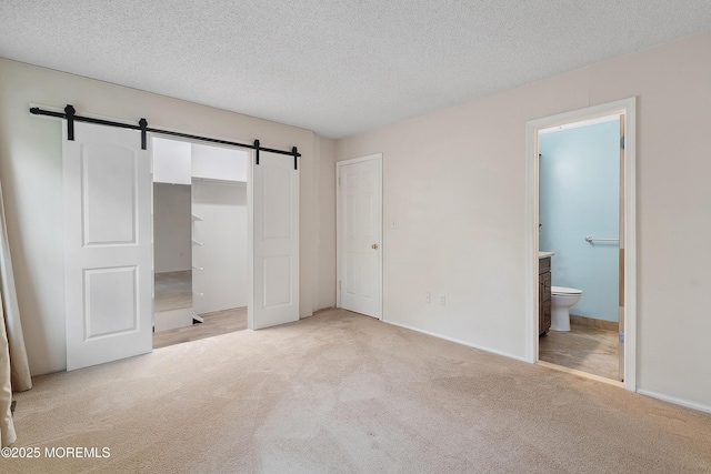 21 Steeple Chase Ct, Tinton Falls, NJ 07724 - unfurnished bedroom with a barn door, light carpet, a textured ceiling, connected bathroom, and baseboards