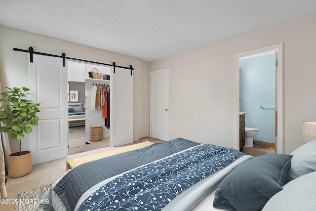 21 Steeple Chase Ct, Tinton Falls, NJ 07724 - bedroom featuring a barn door, a closet, ensuite bathroom, and a textured ceiling