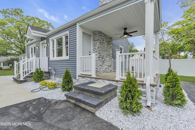 property entrance with a ceiling fan and fence