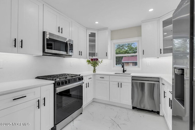 kitchen with stainless steel appliances, a sink, white cabinetry, light countertops, and recessed lighting