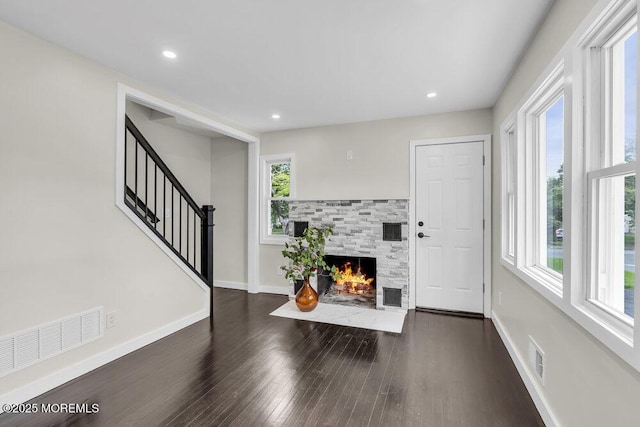 unfurnished living room with dark wood finished floors, baseboards, a fireplace, stairway, and recessed lighting