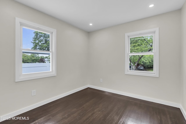 spare room with healthy amount of natural light, dark wood-type flooring, baseboards, and recessed lighting