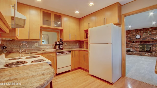 kitchen featuring white appliances, light wood finished floors, recessed lighting, a sink, and a fireplace