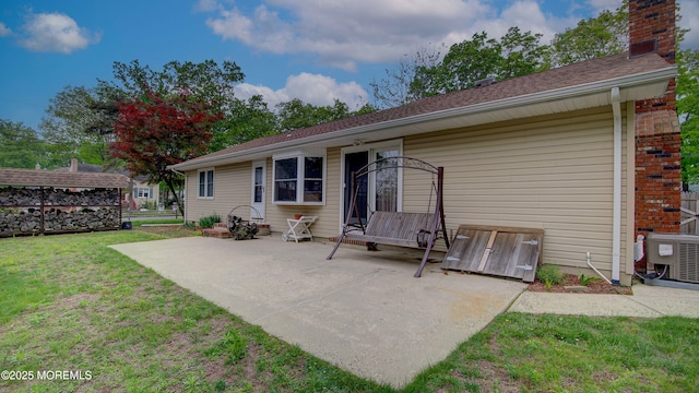 rear view of property featuring a patio area, a lawn, central AC unit, and a chimney