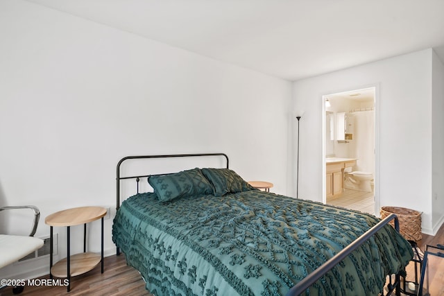 bedroom with wood finished floors, baseboards, and ensuite bath