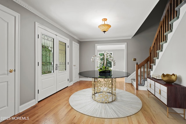 foyer entrance with stairs, light wood-style floors, baseboards, and ornamental molding